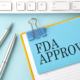FDA APPROVED text on sticker on blue background with pen and keyboard