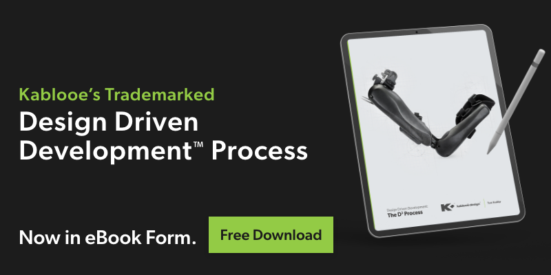 A digital tablet displays an eBook cover with prosthetic limbs. Text reads: "Kablooe’s Trademarked Design Driven Development™ Process. Now in eBook Form. Free Download" on a black background.