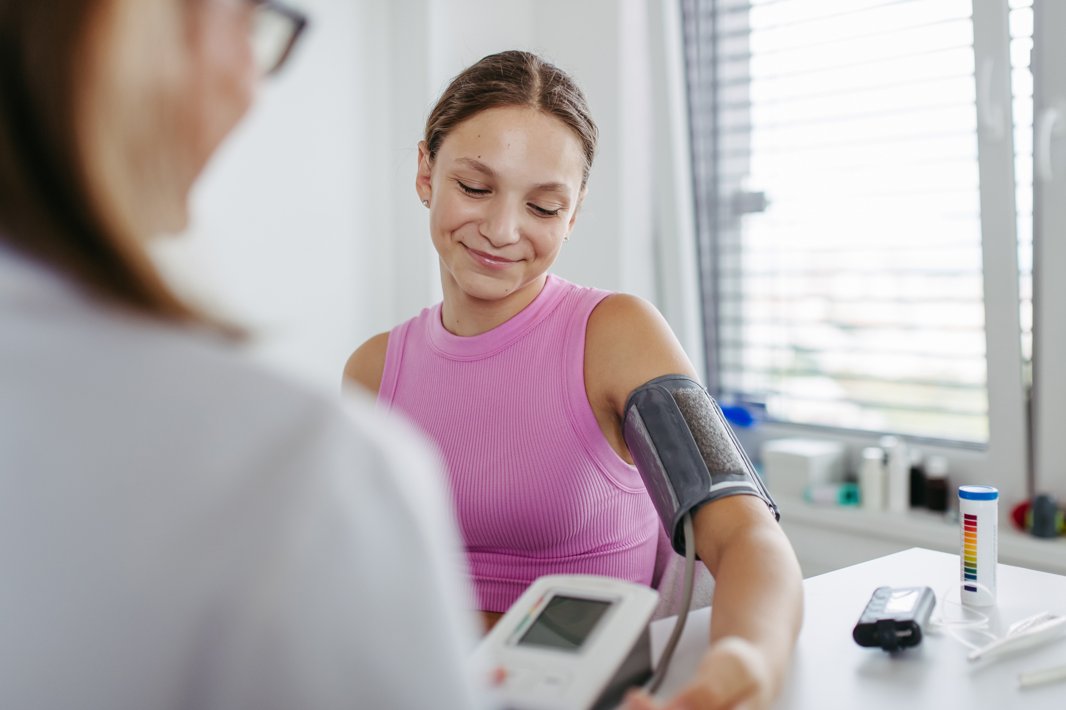 Doctor measuring a patient's blood pressure in clinic. Examining hypertension in diabetic teenage girl. Girl visiting paediatrician for annual preventive examination, check-up.